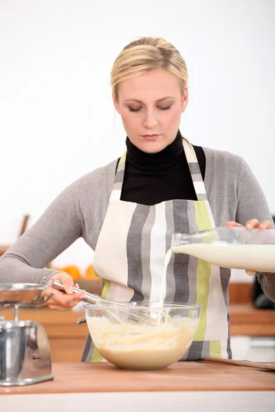 Женщина взбивает смесь на кухне — стоковое фото