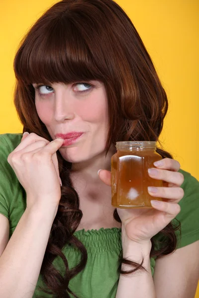 Playful woman eating honey — Stock Photo, Image