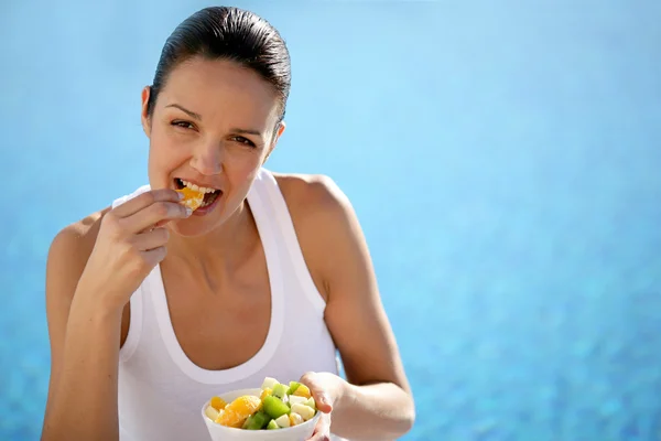 Жінка їсть фрукти у басейні — стокове фото