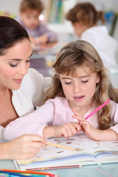 Leraar helpen een klein meisje in de klas — Stockfoto