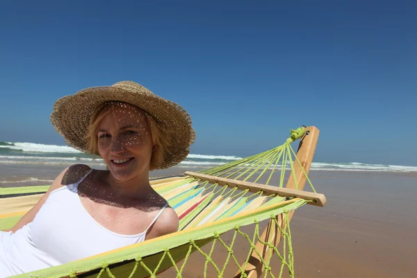 Женщина в соломенной шляпе отдыхает на гамкоке на пляже — стоковое фото