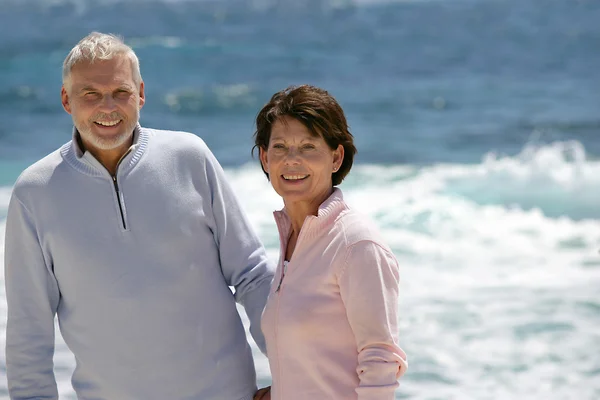 ビーチで散歩を楽しんでいる高齢者のカップル — ストック写真