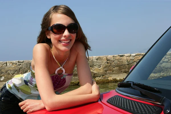 Lachende vrouw leunend op een auto — Stockfoto