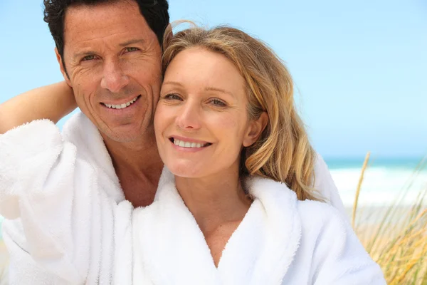 Счастливая пара в халатах на пляже — стоковое фото