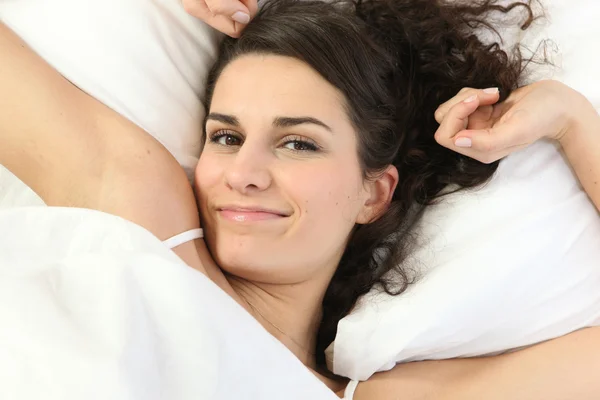 Женщина лежит в постели растягивая — стоковое фото