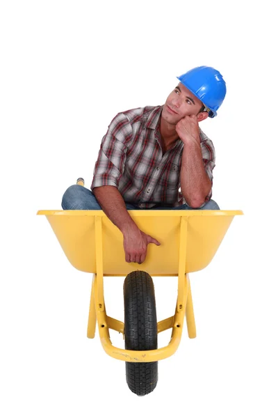 Dreamy laborer sitting in a wheelbarrow — Stock Photo, Image