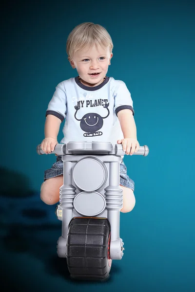 Мальчик на пластиковом мотоцикле — стоковое фото