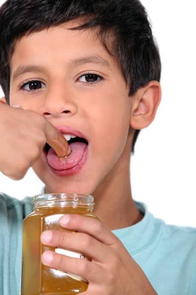 Boy tasting some honey — Stock Photo, Image
