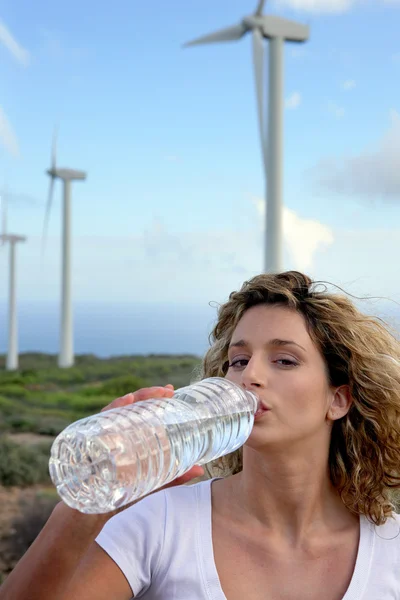Жінка п'є воду біля вітрових турбін — стокове фото