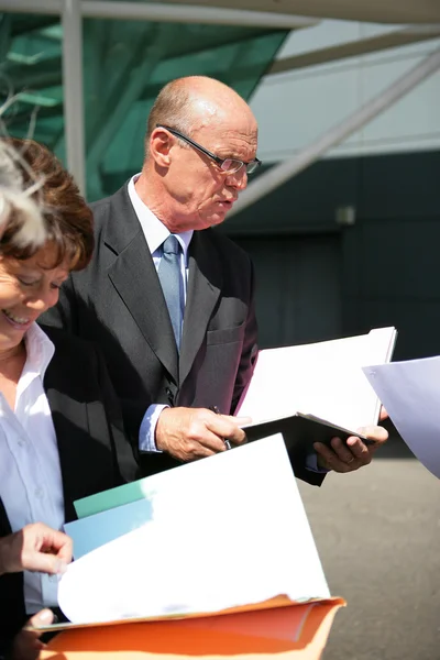 Senior businessman and businesswoman reading documents — Stock Photo, Image