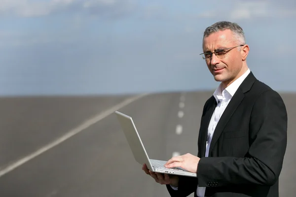 Man with laptop stood on road — Stock Photo, Image