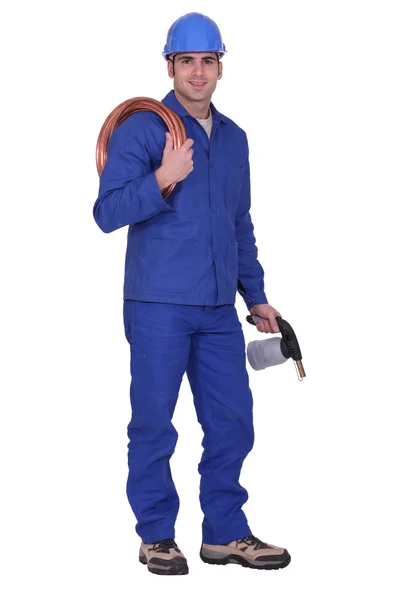 Homem segurando tubulação de cobre e maçarico — Fotografia de Stock