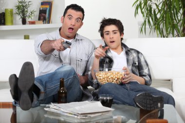 Father and son watching television together clipart