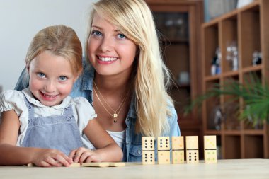Mother and daughter playing dominoes clipart