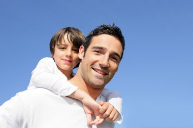 Boy riding piggy back on his father's back clipart