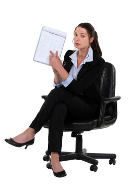 Woman sitting on chair pointing at clipboard clipart