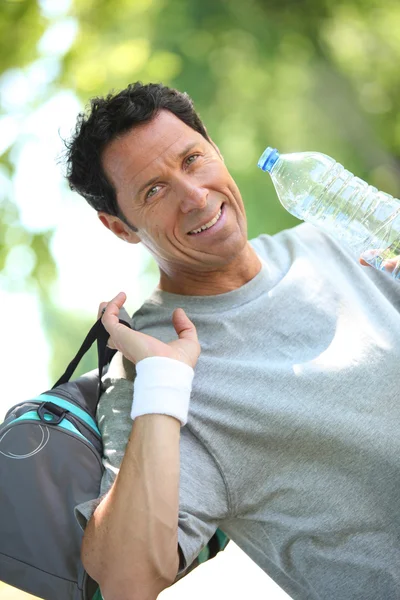 Uomo dall'aspetto sportivo che beve da una grande bottiglia d'acqua — Foto Stock