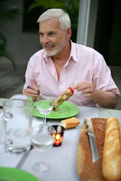 Senior man on vacation eating in a restaurant — Stock Photo, Image