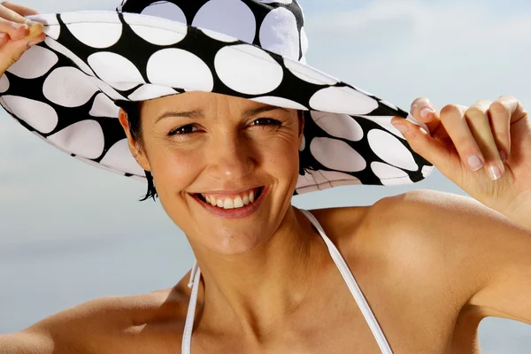 Симпатичная брюнетка в пятнистой шляпе на пляже — стоковое фото