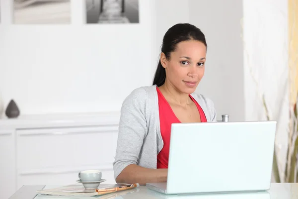 Kadın kahve bir fincan ile laptop yanında oturdu. — Stok fotoğraf