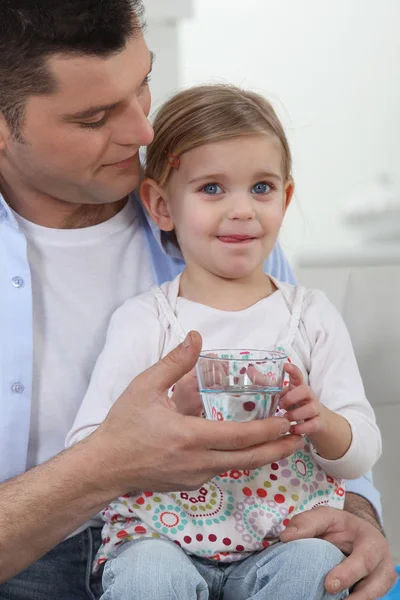 Man with little girl drinking glass of water — Stock Photo, Image