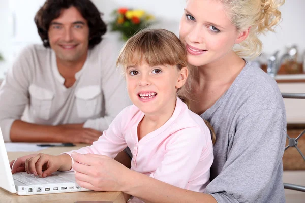 Szülők és a lánya, egy laptop számítógép használata — Stock Fotó