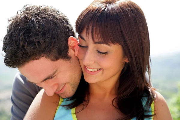 Cabeza y hombros de una joven pareja abrazándose al sol — Foto de Stock