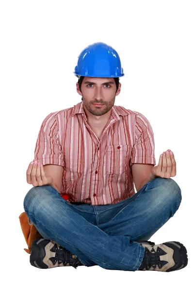 A construction worker in the lotus position. — Stock Photo, Image