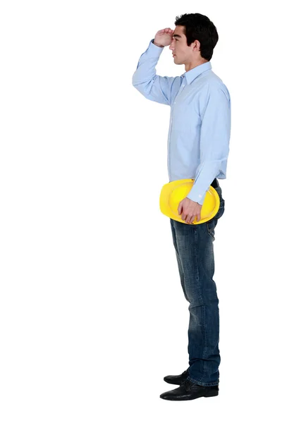 Young man with a hardhat looking into the distance — Stock Photo, Image