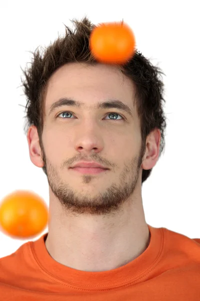 Man throwing tangerines into the air — Stock Photo, Image