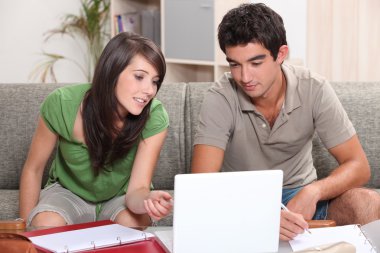 Young couple sitting on a sofa with a laptop clipart