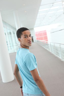 Young man walking down an empty corridor clipart