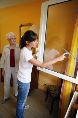 Young woman helping senior woman doing chores clipart