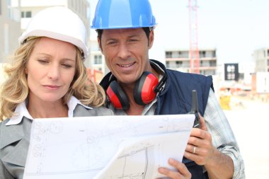 Construction worker looking at an engineer's drawing clipart