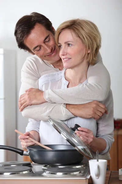 Człowiek przytulanie kobieta gotowania w kuchenkę elektryczną — Zdjęcie stockowe