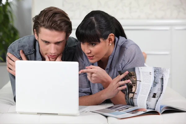Casal olhando para uma brochura e um laptop — Fotografia de Stock