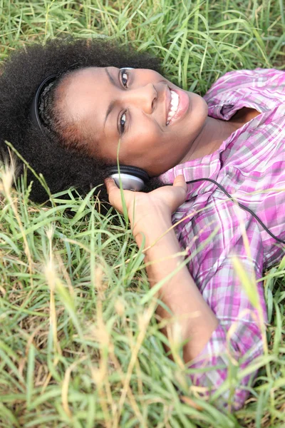 Vrouw die in veld luisteren naar muziek — Stockfoto