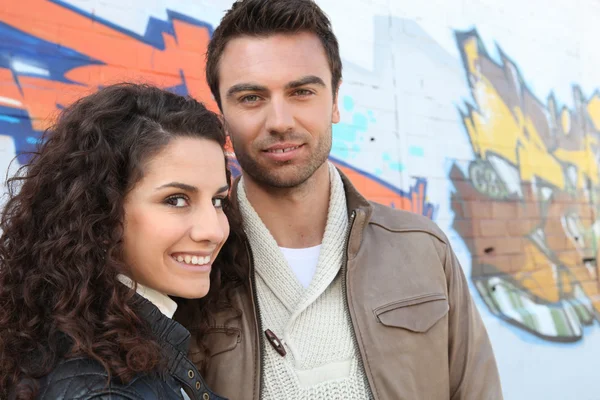 Jeune couple devant un mur de graffiti — Photo