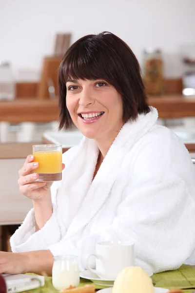 Женщина в халате с апельсиновым соком — стоковое фото
