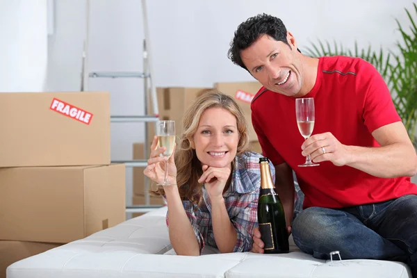 Couple holding champagne glasses boxes in background — Stock Photo, Image