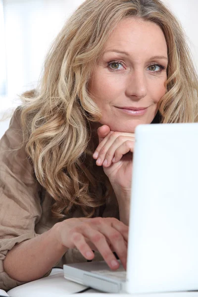 Attractive blonde haired woman using a laptop computer — Stock Photo, Image