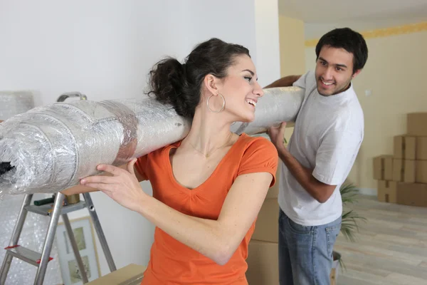 Couple portant un nouveau tapis enroulé dans la maison — Photo