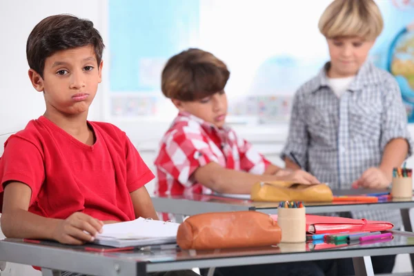 Little boy sighing in a classroom — Stock Photo, Image