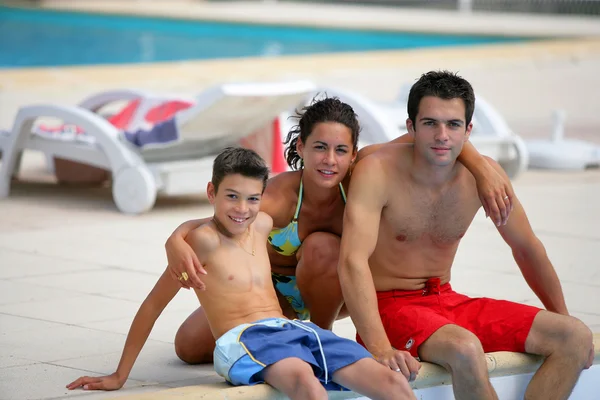 Familia sentada junto a una piscina — Foto de Stock