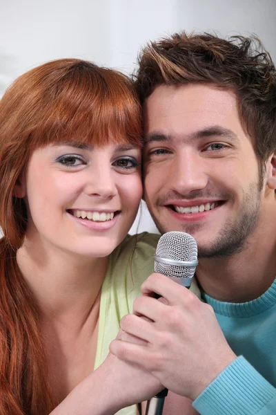 Young couple with a microphone — Stock Photo, Image