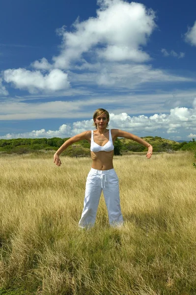 Frau praktiziert Yoga auf einem Feld — Stockfoto