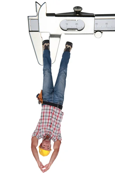 Montage of a laborer hung to callipers — Stock Photo, Image