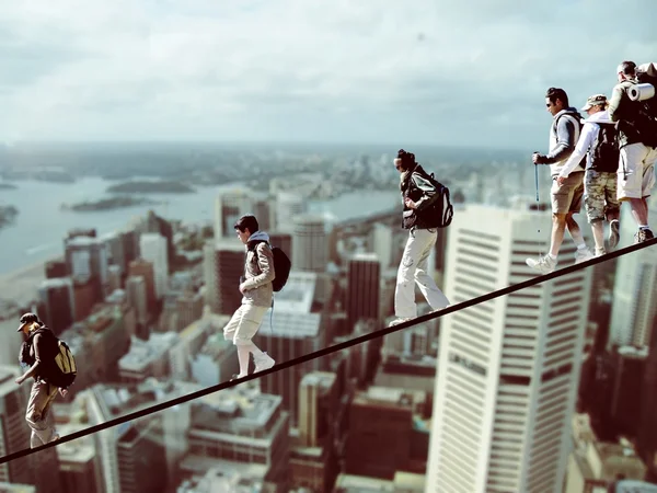 Scalatori su una corda con paesaggio urbano sullo sfondo, fotomontaggio — Foto Stock