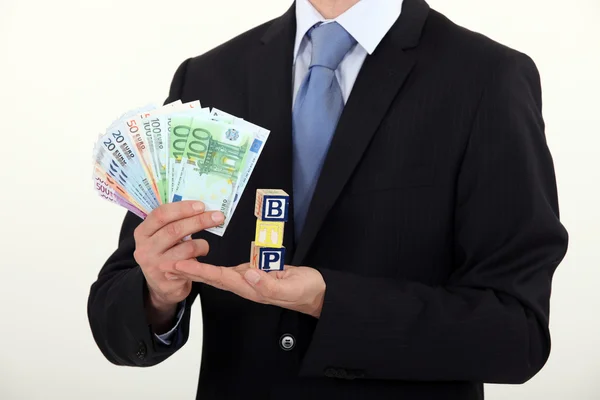 Man holding toy blocks and money — Stock Photo, Image