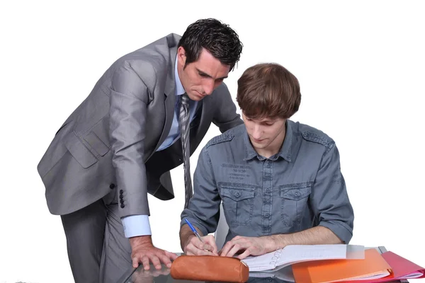 Teacher helping a student with his studies — Stock Photo, Image